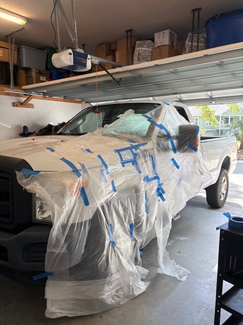 Ford F-350 masked and wrapped for paint preparation in garage