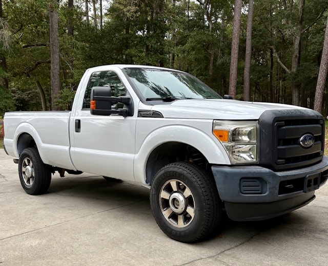 Ford F-350 truck freshly repainted white, highway markings removed, before new wheels and leveling kit