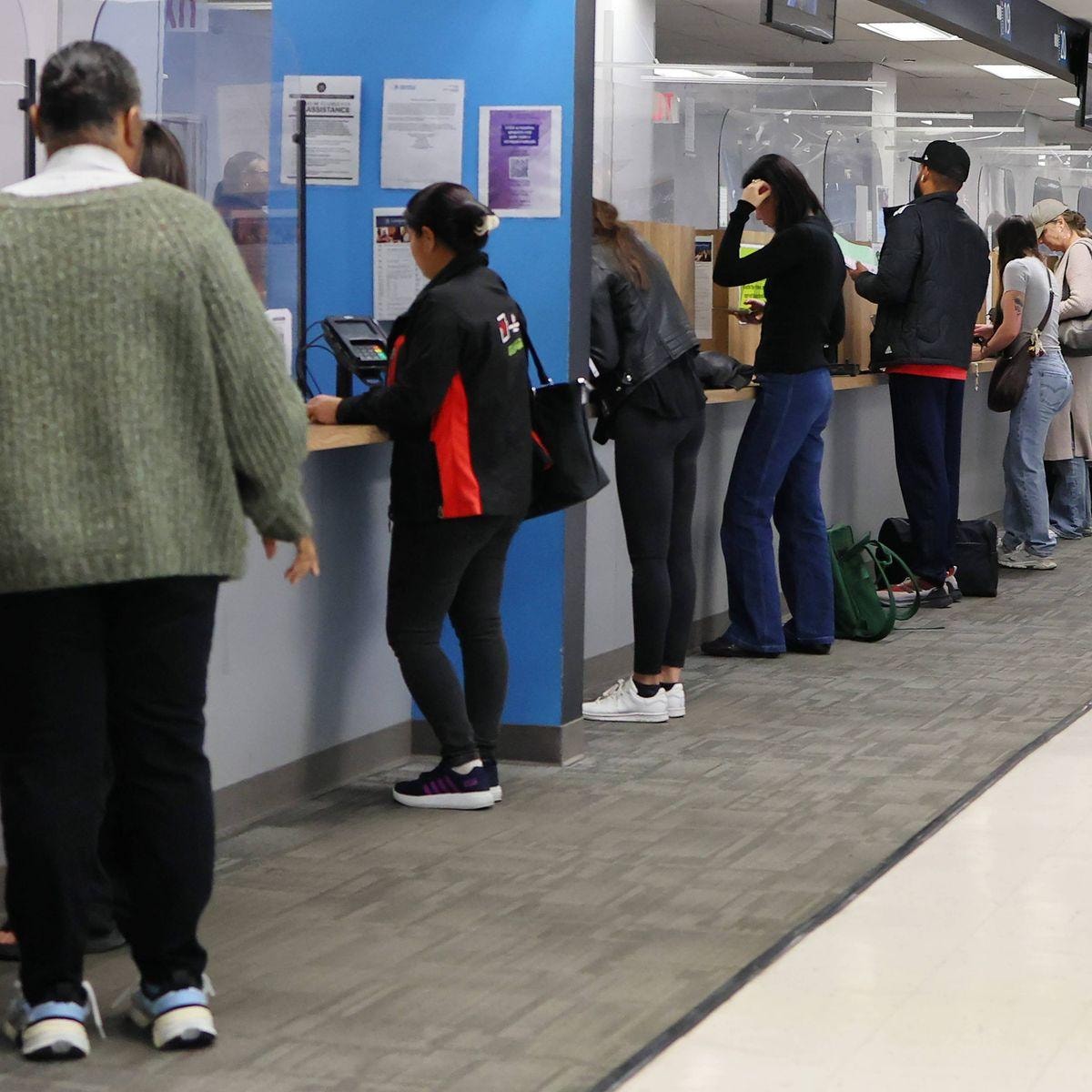 People at DMV service windows processing title and registration paperwork
