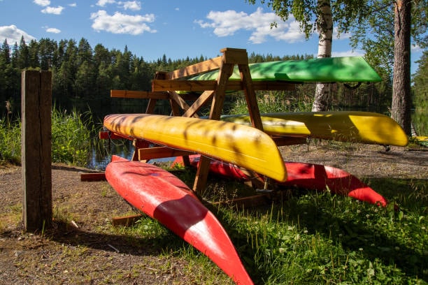 Colorful kayaks stacked on a wooden rack outdoors near a lake