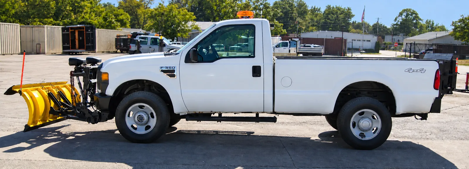 A white Ford F-350 4x4 regular cab with a yellow snow plow mounted on the front, driver side