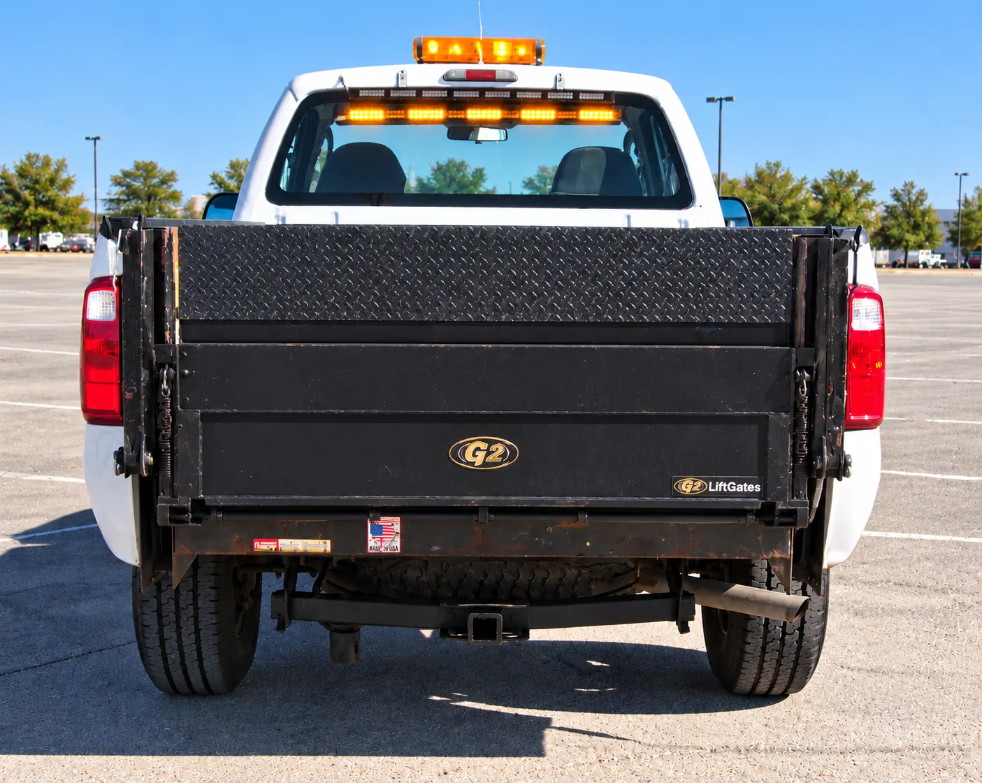 The rear of the Ford F-350 with a G2 liftgate, amber light bar and a tow hitch