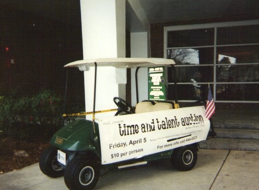 A green EZ-GO golf cart with an auction banner on display