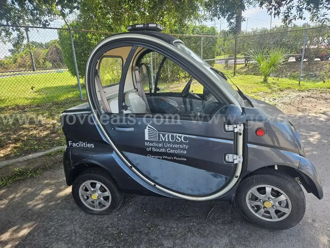 An enclosed electric low-speed vehicle with Medical University of South Carolina Facilities markings and a roof light bar