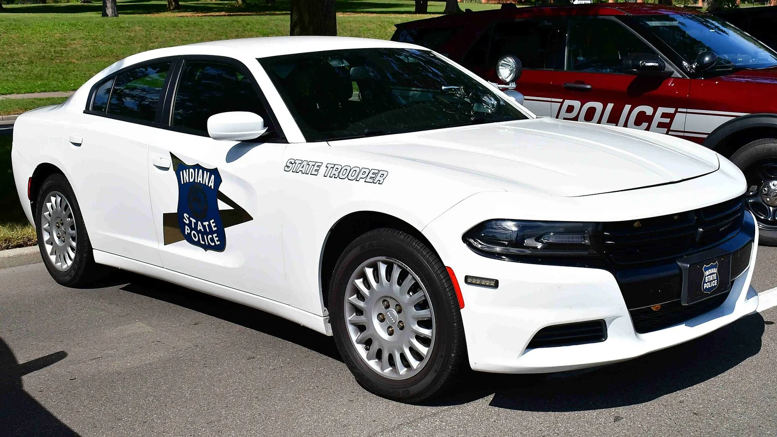 A white Indiana State Police Dodge Charger Pursuit with the State Trooper door lettering, front three-quarter view.