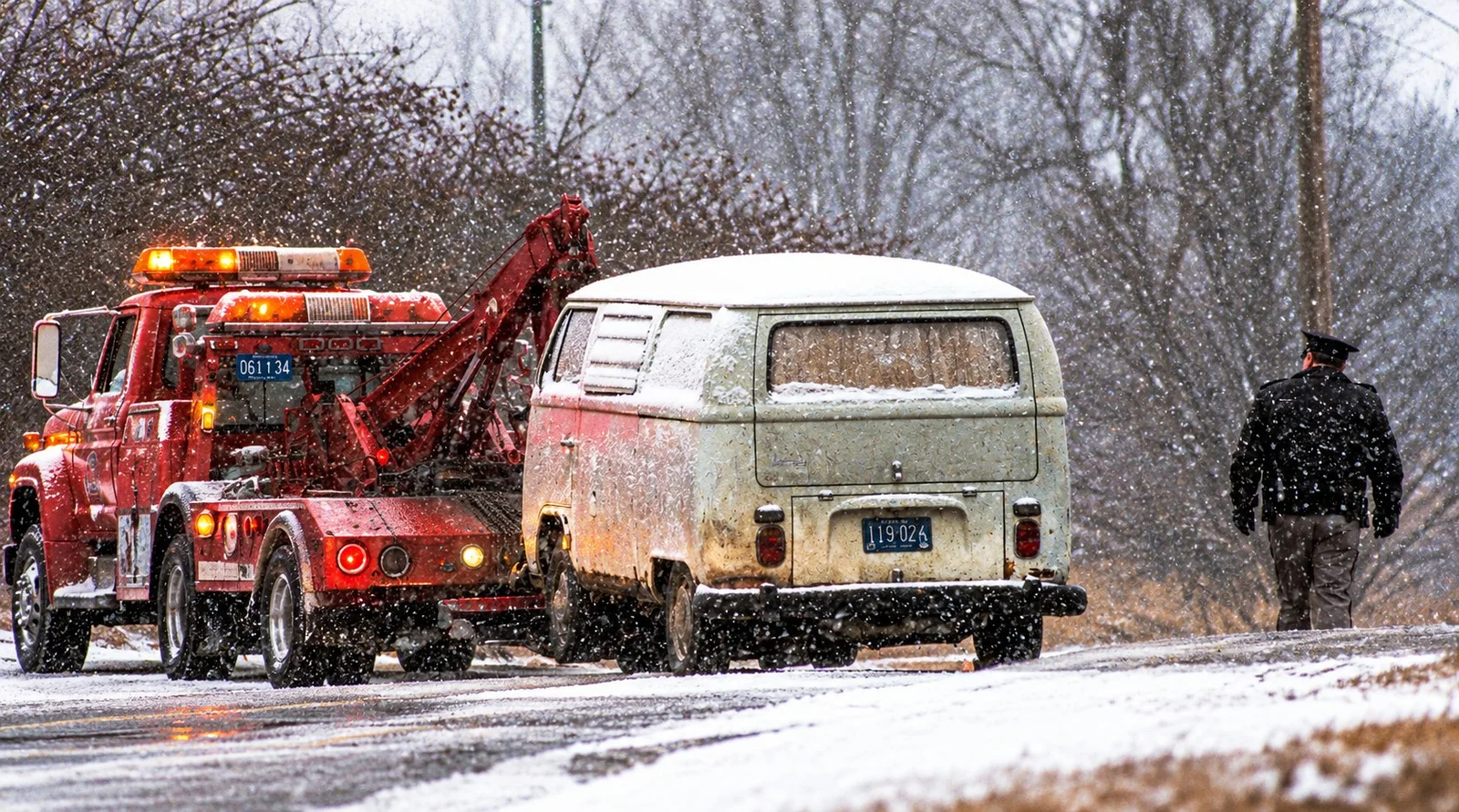 A tow truck hauls Kevorkian's white Volkswagen van through falling snow as an officer walks away