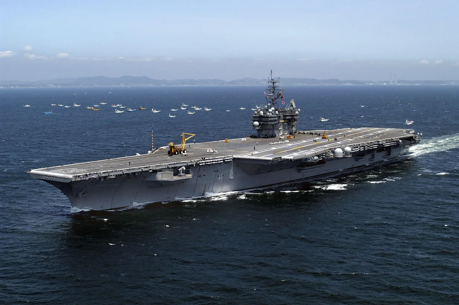 USS Kitty Hawk (CV-63) underway off Japan with fishing boats in the background