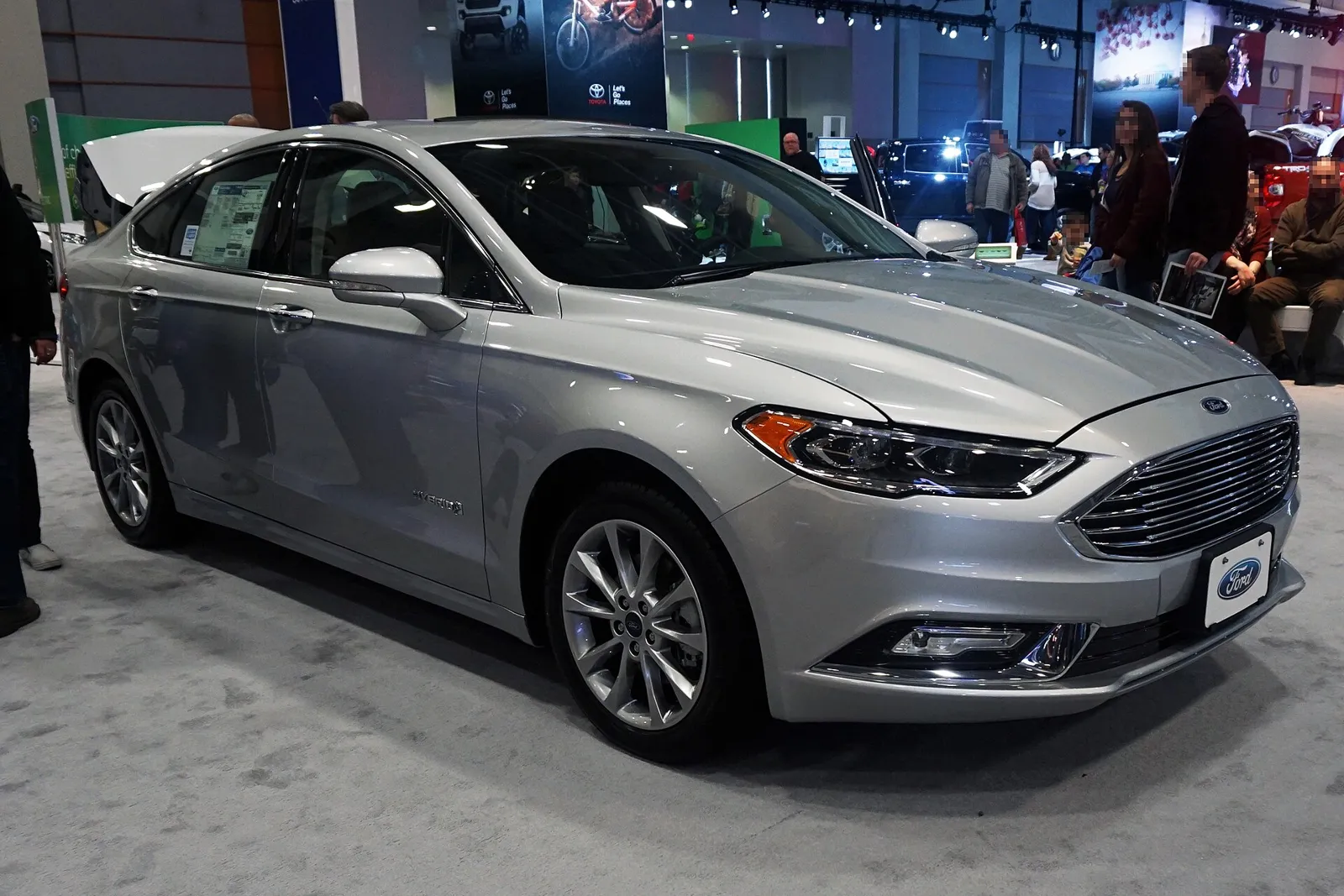 A silver 2017 Ford Fusion Hybrid sedan on a show floor.