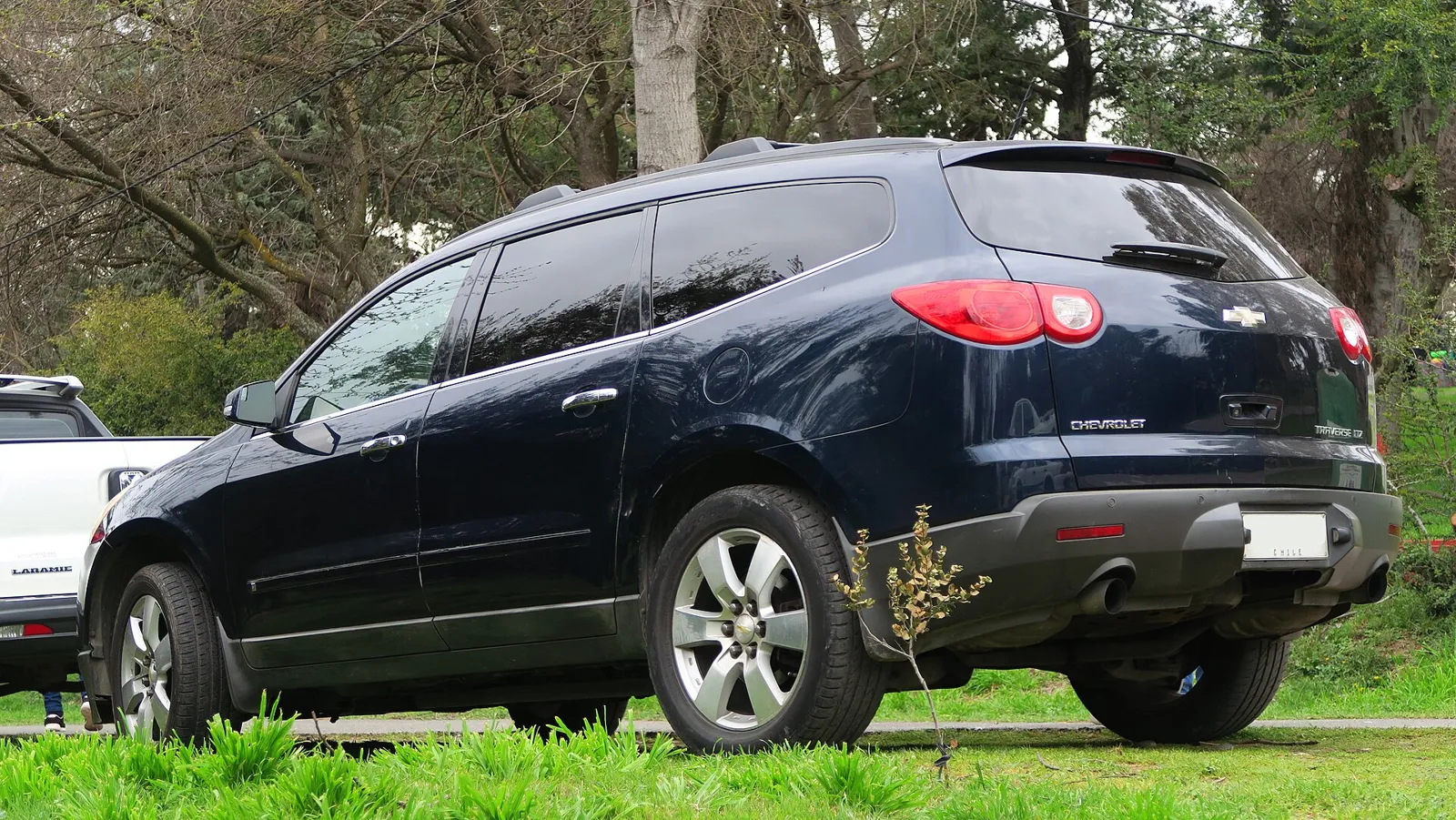 A dark 2015 Chevrolet Traverse LTZ, rear three-quarter view, parked on grass.