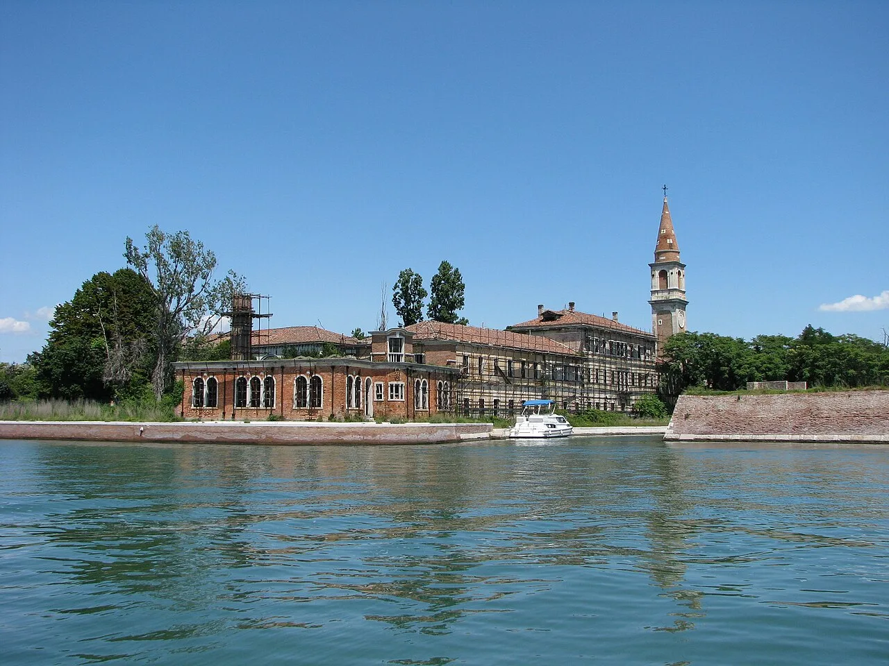 Poveglia seen across the water, with its brick buildings, bell tower and boat landing