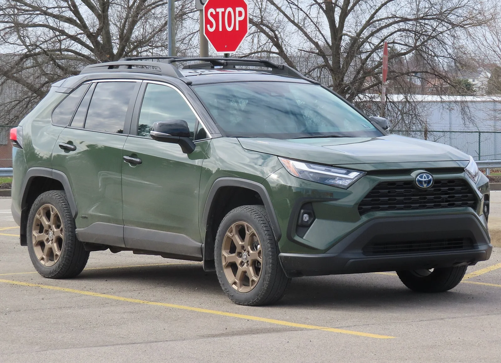 A green 2024 Toyota RAV4 Hybrid Woodland Edition, front three-quarter view, in a parking lot.