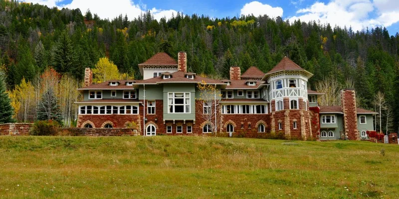 Redstone Castle in autumn, its red sandstone and green shingles set against a forested mountainside