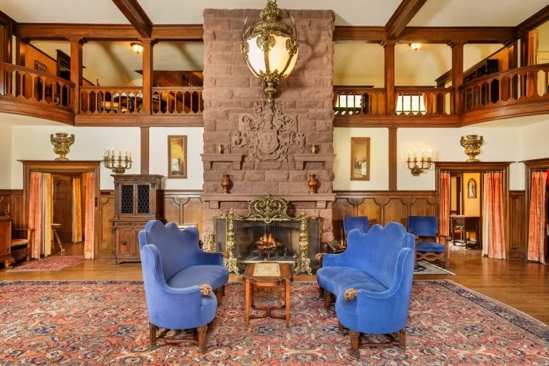 The Great Hall of Redstone Castle with its stone fireplace, balcony and blue velvet chairs