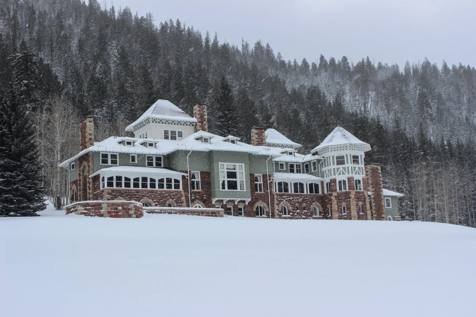 Redstone Castle under fresh snow with pine-covered mountains behind it