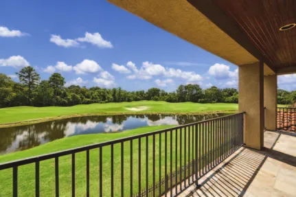 A covered second-floor balcony looking out over a golf course fairway and pond.