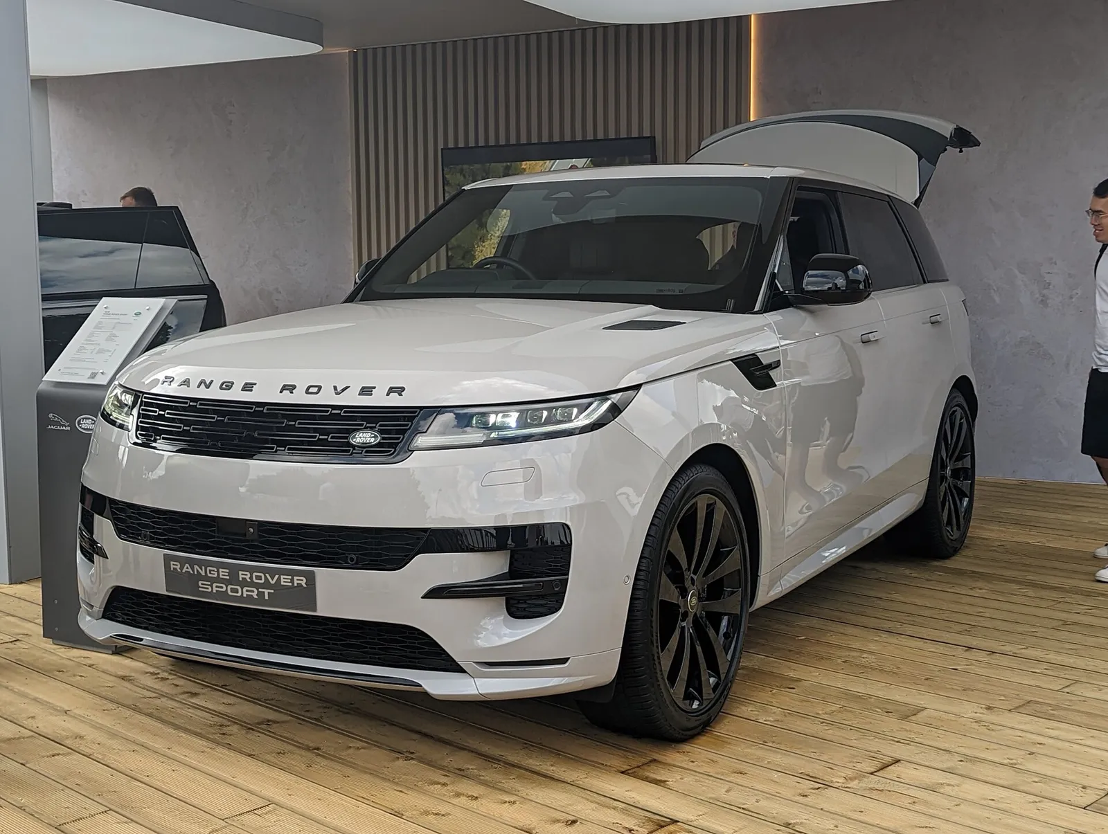 A white 2022 Range Rover Sport with the tailgate open, in a showroom.