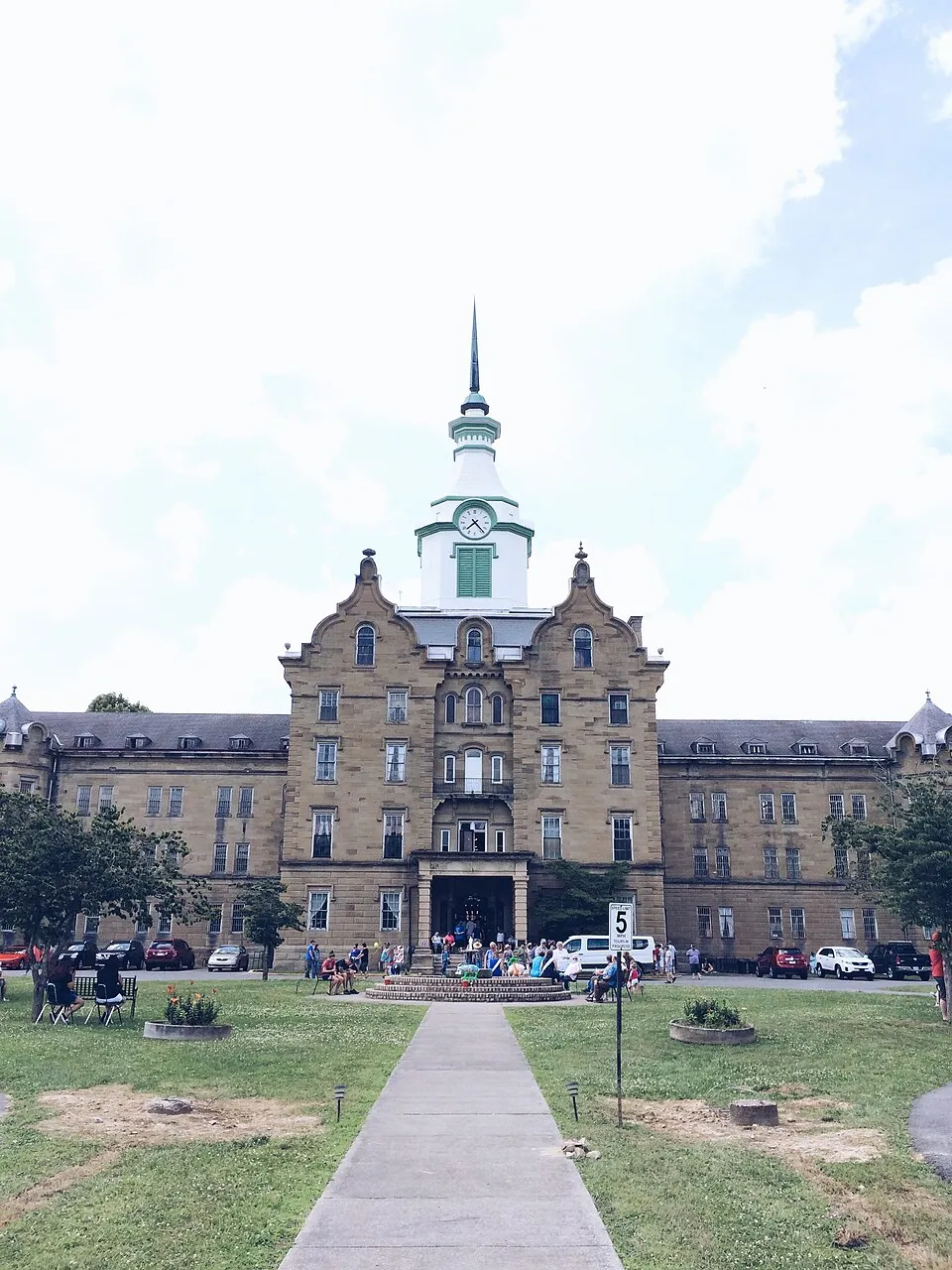 Visitors gather at the front entrance beneath the clock tower, and a restored Victorian parlor inside the main building.