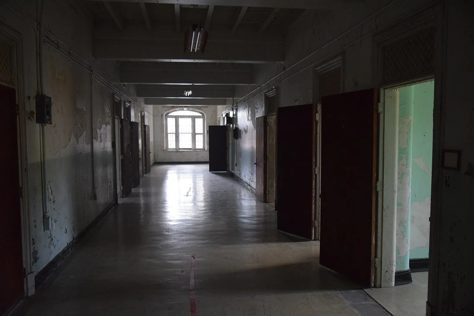 The hand-cut stone and clock tower seen through an original window, and a long ward hallway lined with open doors.