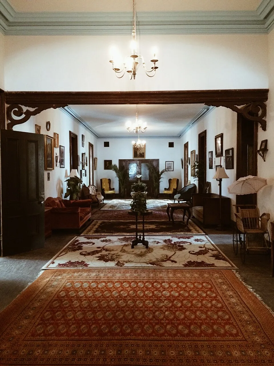 Visitors gather at the front entrance beneath the clock tower, and a restored Victorian parlor inside the main building.