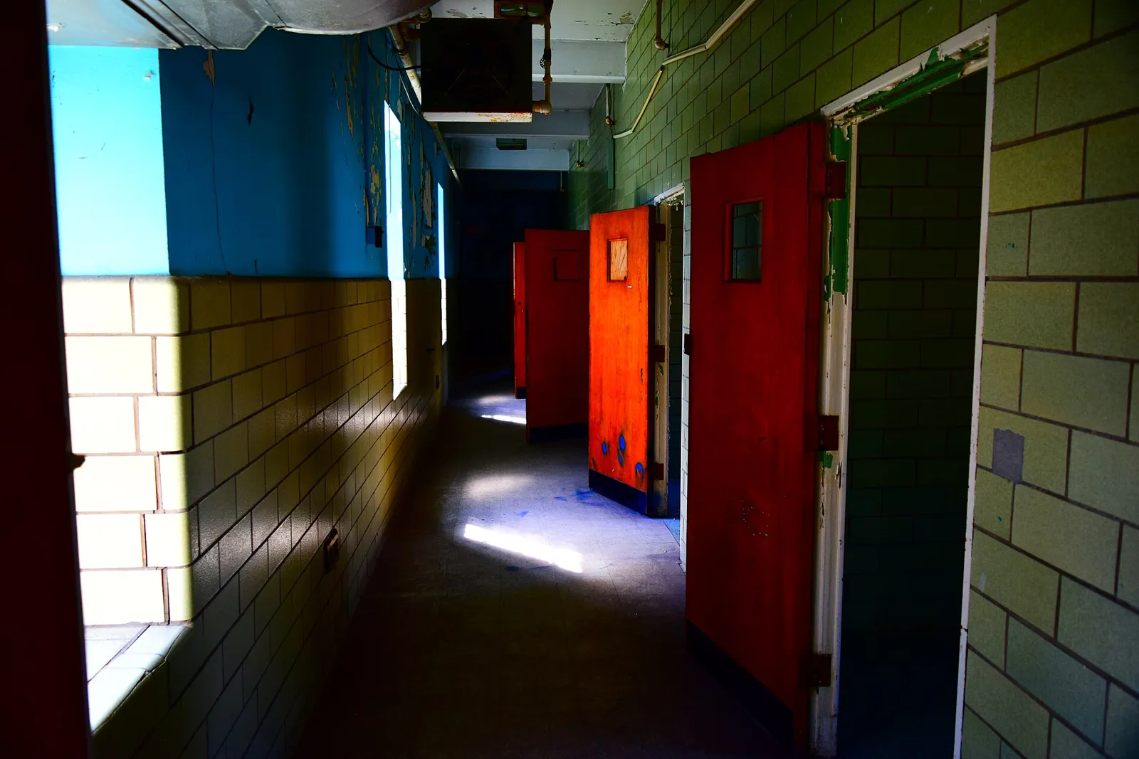 A brightly painted hallway with red doors inside the asylum