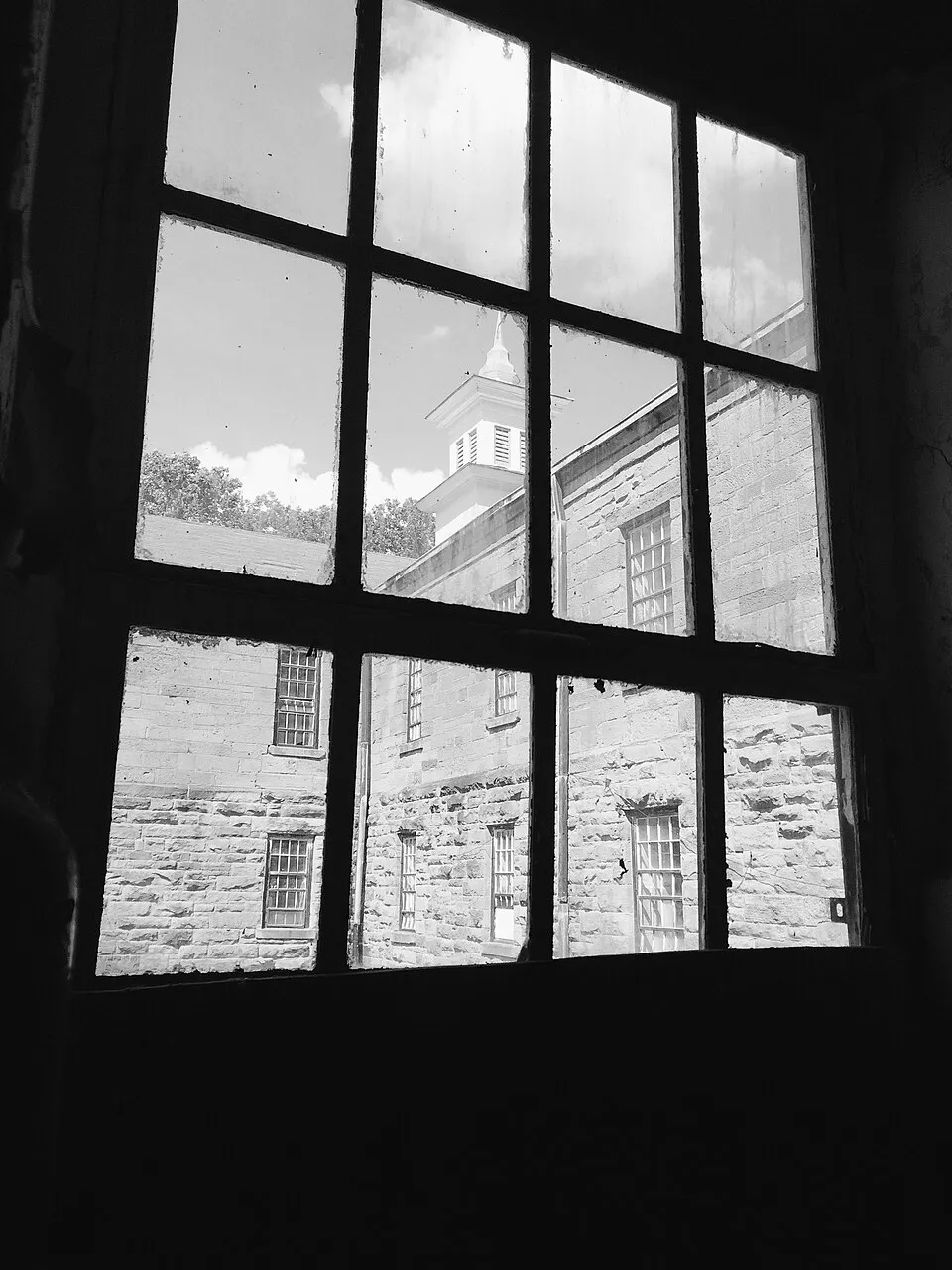 The hand-cut stone and clock tower seen through an original window, and a long ward hallway lined with open doors.